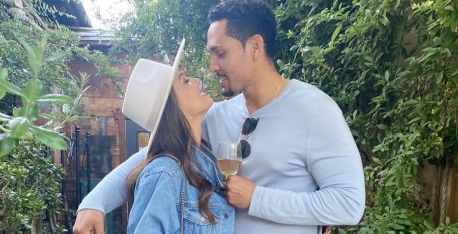 A woman smiles at a man with his arm around her shoulder