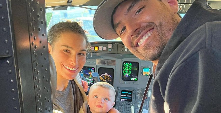 A man and a woman with their baby in an airplane cockpit
