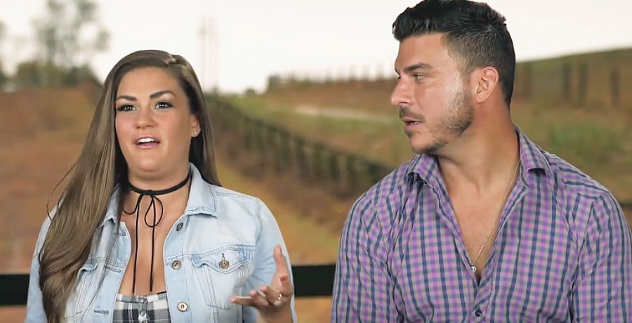 A woman with brown hair next to a man in a purple shirt 