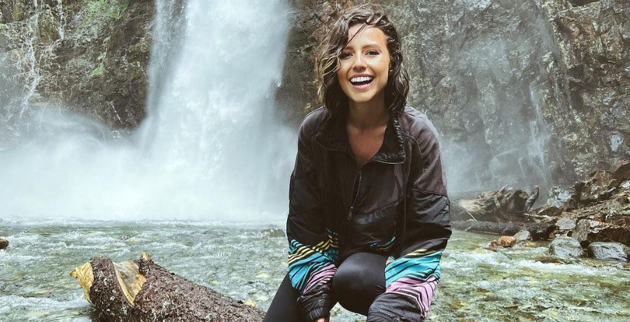 A woman with short brown hair in front of a waterfall