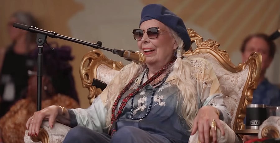 An older woman sitting down in front of a microphone.