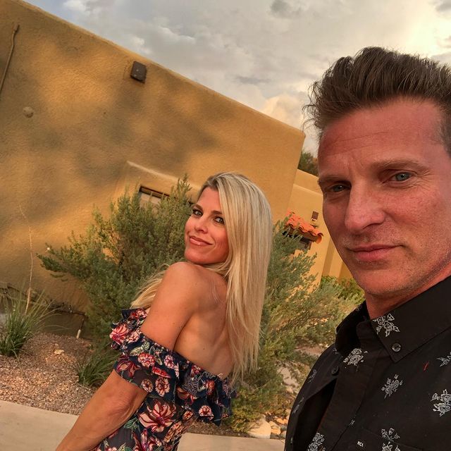 A woman with long blonde hair standing with a man with short brown hair.